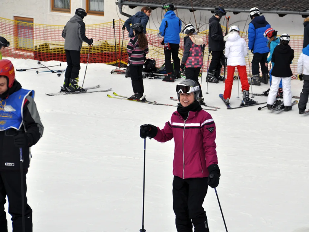 Skifahrerin in dunkelroter Jacke am Pistenrand.